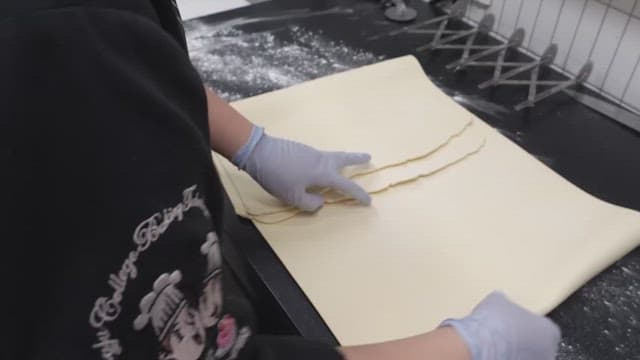 Folding dough sheets on a floured work surface in the kitchen