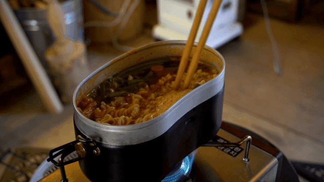 Ramen boiling in a mess tin pot on the stove