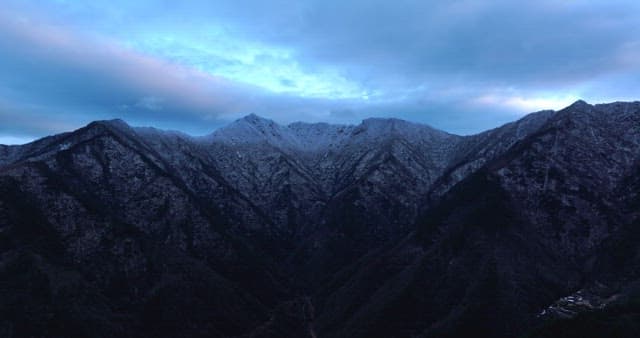 Snow-covered mountains under cloudy skies