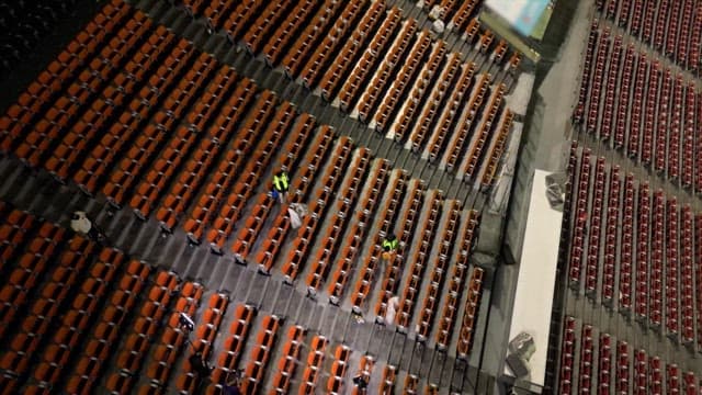 빈 경기장의 좌석을 청소하는 사람들