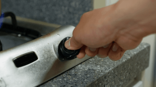 스토브 손잡이를 조정하는 손