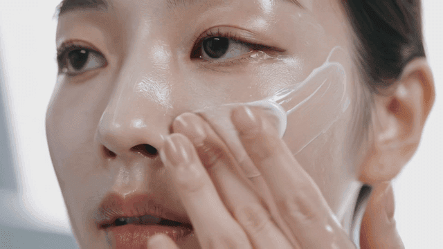 Young woman applying skincare cream to her face