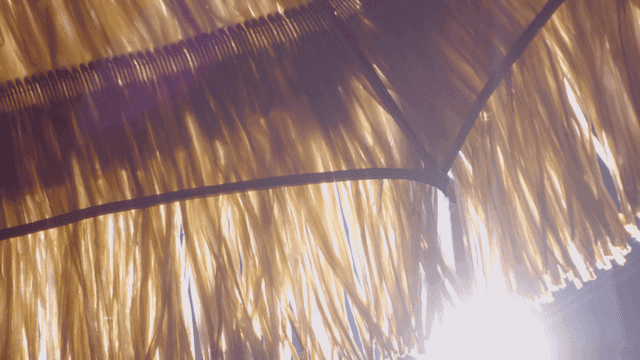 Sunlight filtering through a straw umbrella