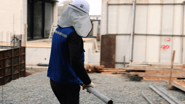 건설 현장에서 금속 파이프를 나르는 작업자