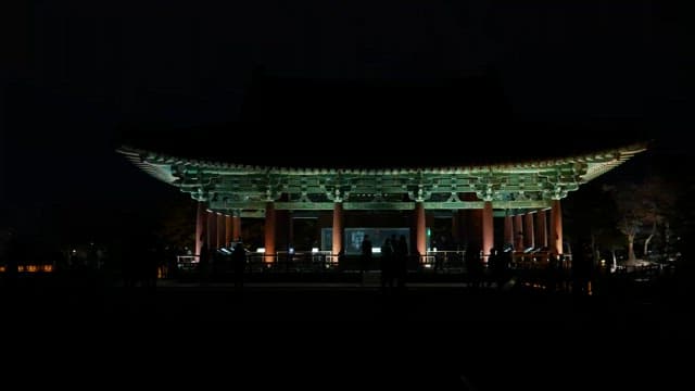 Ancient pavilion lit up at night with people