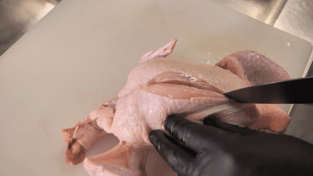 Cutting raw chicken on a cutting board
