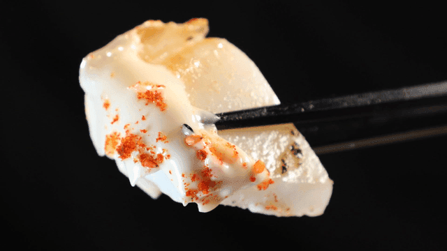 Chopsticks picking up grilled squid seasoned with mayonnaise