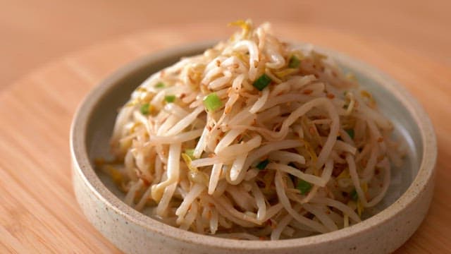 Bean sprout seasoning in a ceramic bowl on a wooden table