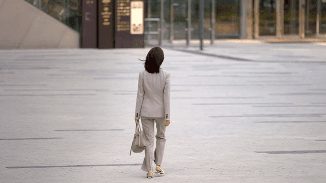 Back view of office worker walking in modern city square