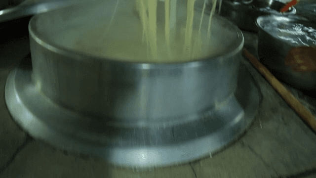 Boiling Noodles in a pot placed over a traditional furnance