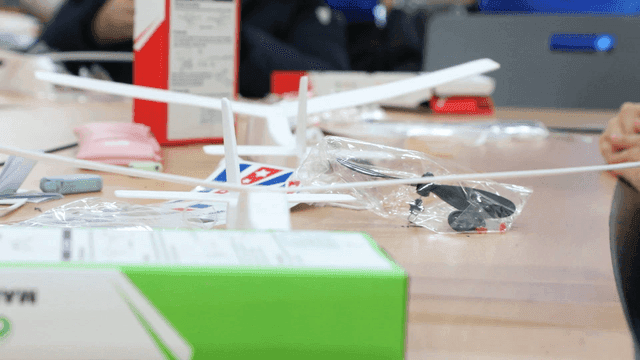 Students assembling model airplanes on classroom desks