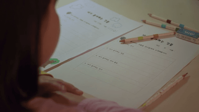 책상에서 종이를 보며 고민하는 아이