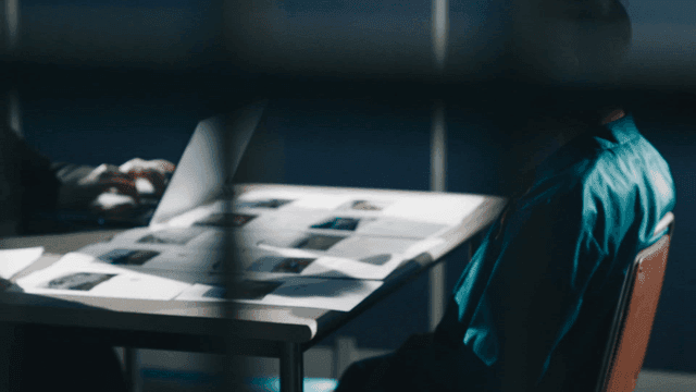 Prisoner being questioned in interrogation room beyond bars