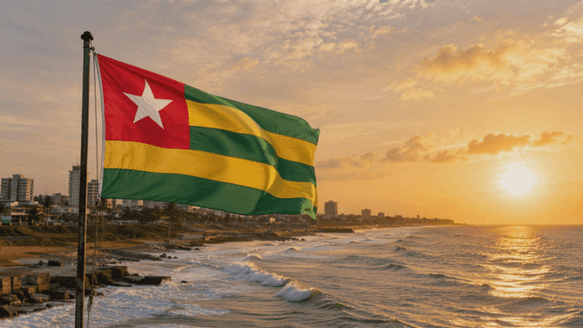 Flag of Republic of Togo fluttering on seashore at sunset