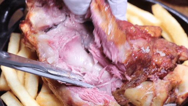 Juicy pork being sliced with fries