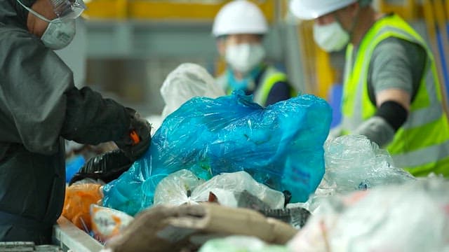 Workers sorting mixed waste on a recycling conveyor belt