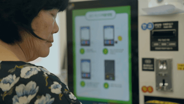 An elderly woman using a digital kiosk indoors