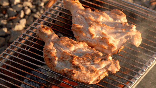 Chicken grilling on a barbecue with flames