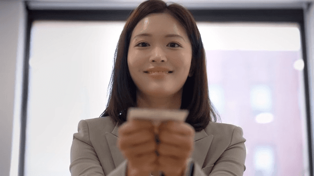 Woman in suit handing over business card