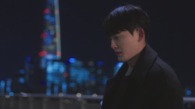 밤에 도시의 불빛을 배경으로 난간 옆에 서 있는 남자