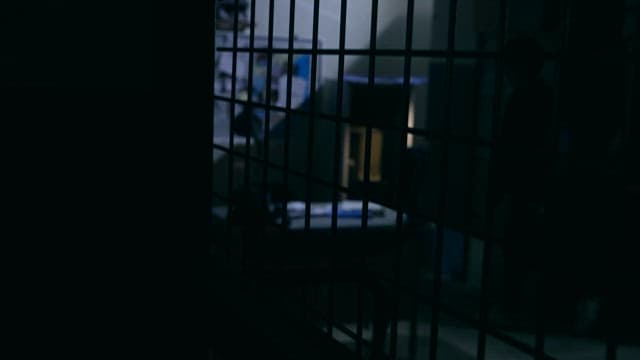 철창 사이로 보이는 어두운 사무실의 고독한 실루엣