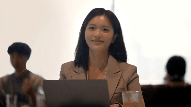 Female office worker smiling while looking straight ahead in cafe