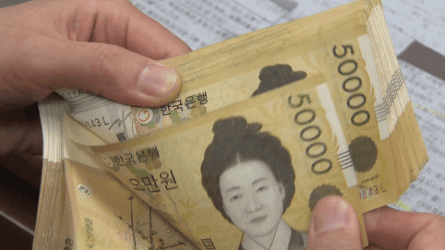 Hands counting 50,000 won bills on desk