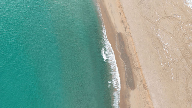 Quiet sandy beach with waves and rocks