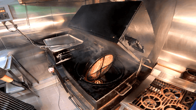 Meat grilled on rotating barbecue in kitchen