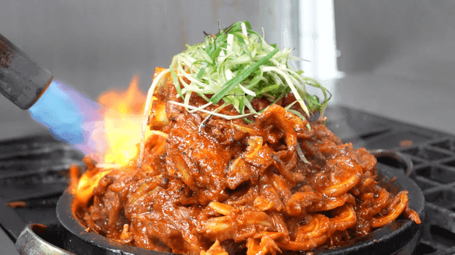 Torch grilling spicy crunchy braised pork ribs with flame