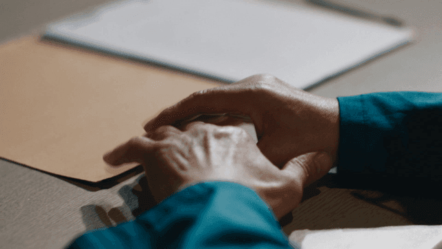 Hands resting on desk with documents
