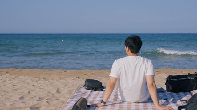 Man Sitting Alone on a Quiet Beach