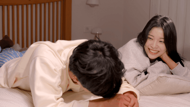 Couple relaxing on bed with gentle smiles
