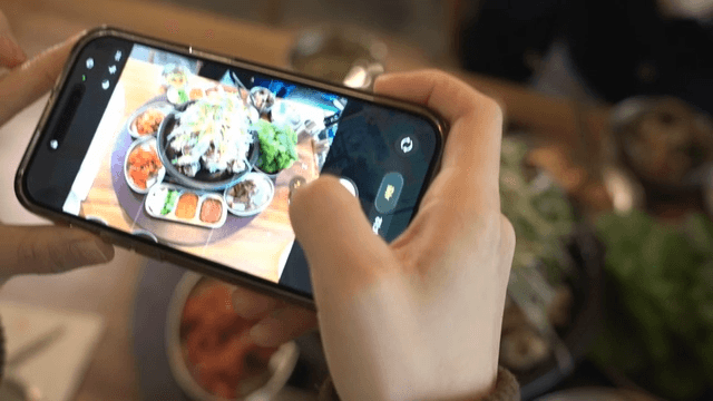 Fried pork jowl taking photo with cell phone on table