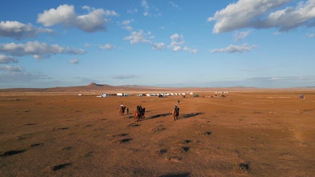 People riding camels in a vast desert landscape