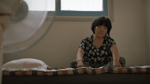 실내에서 침대에 앉아 있는 노인 여성