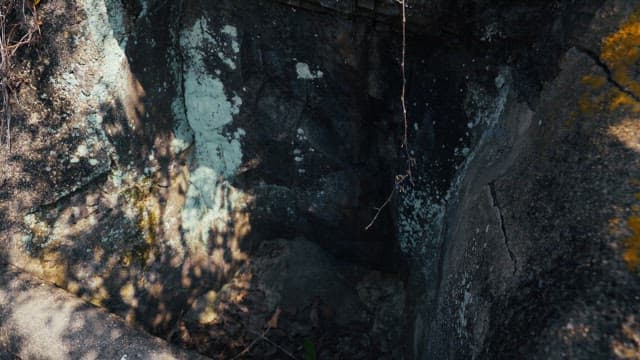 Old spring water source made of rock with a green name tag