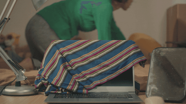 줄무늬 천으로 덮인 노트북과 이불 정리하는 여성