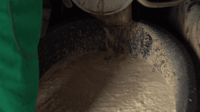 Ground acorn liquid poured into a large black basin
