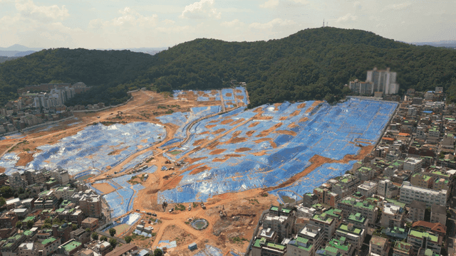 Construction site covered with blue tarpaulin at foot of mountain