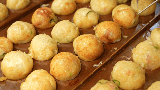Round takoyaki flipping on hot griddle