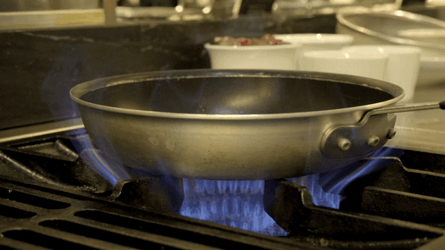 Frying pan over kitchen gas stove flame