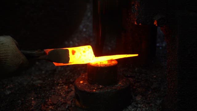 Worker forging metal in a factory