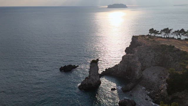 Rocky coastline with sunlight reflecting on the sea