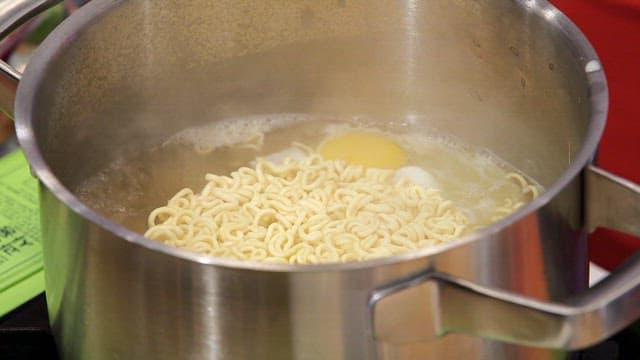 Ramyeon boiling with an egg in a pot