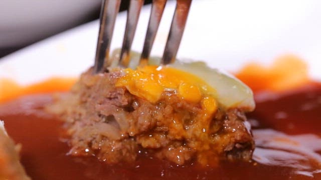 Fork holding a juicy hamburger steak