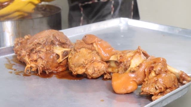 Cooking process of simmered pig's feet with gloved hands