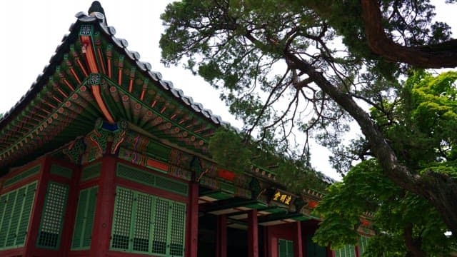 Junmyeongdang Hall of Deoksugung Palace in harmony with trees under a cloudy sky