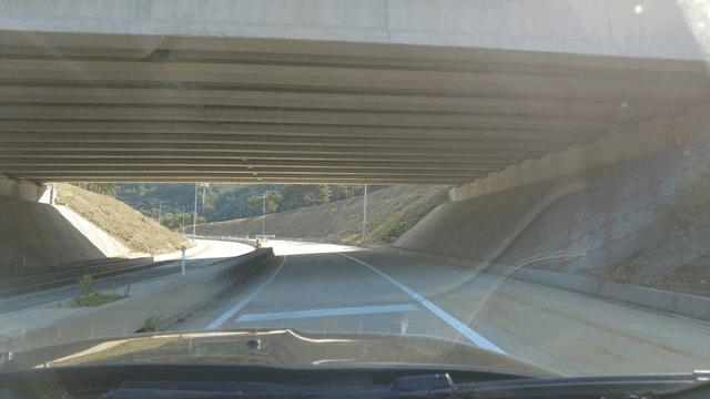 A car driving under a highway bridge