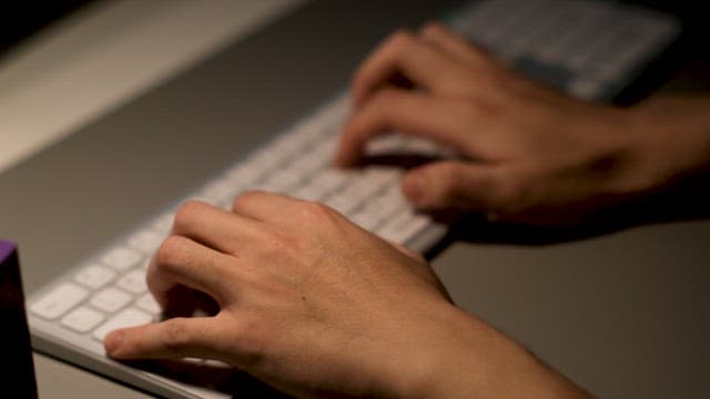 Hands Typing on Keyboard at Desk with Stand On